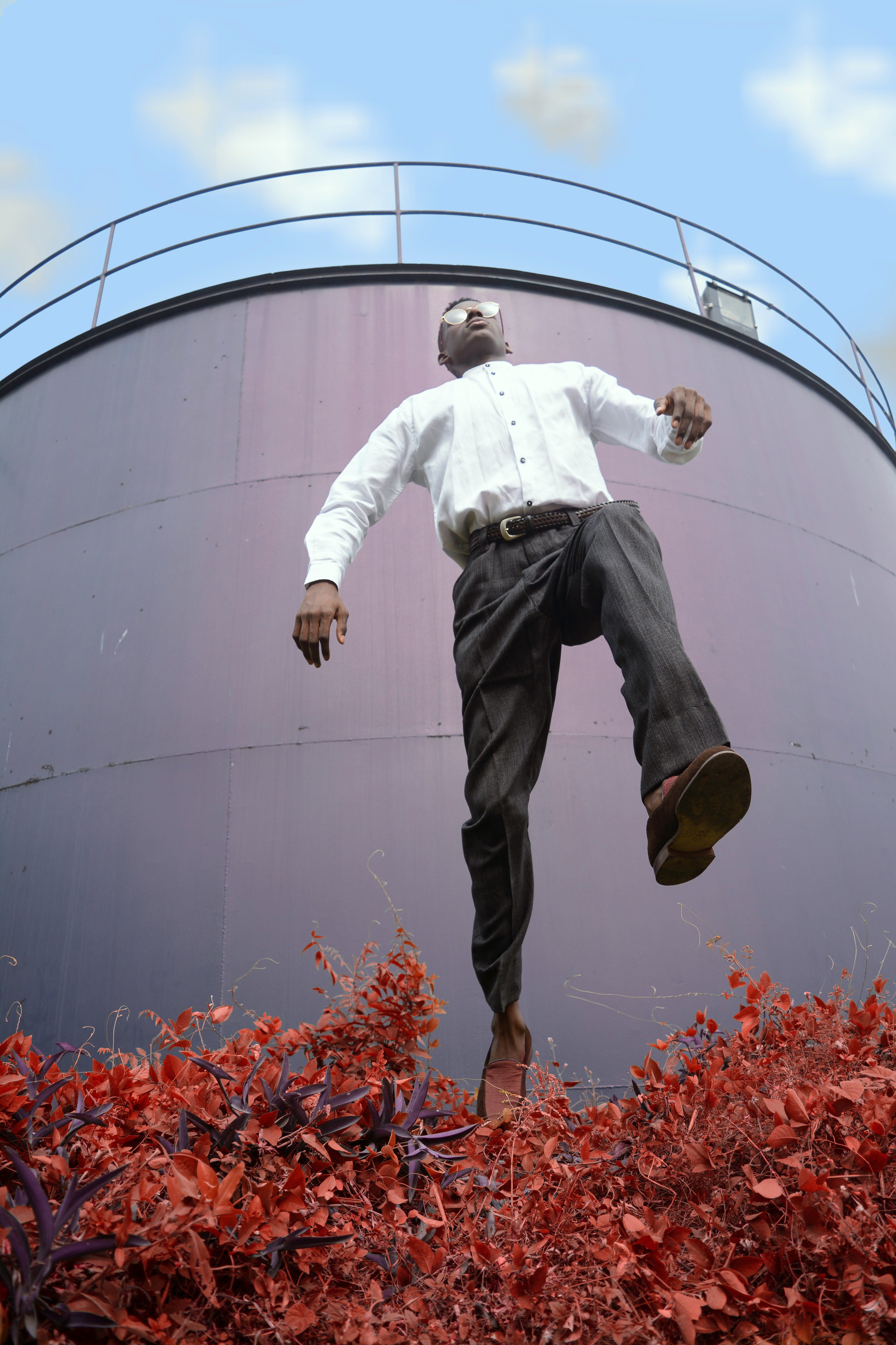 man in white dress shirt jumping over the plant